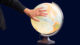 Hand fährt über einen Globus. Element aus dem Beispiel Erklärvideo.